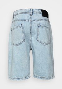 Hellblaue Jeansshorts mit einem verblassten Muster. Verfügt über zwei Gesäßtaschen und ein schwarzes Taillenlabel. Der Saum ist umgeschlagen.