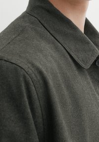 Overhemd met knopen van donkergrijze stof, met een brede kraag, gladde textuur, zichtbare stiksels en een sluiting met een enkele knoop.