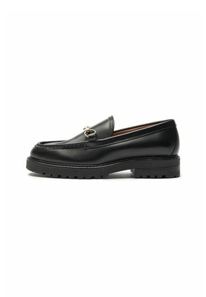 Czarny skórzany loafer z metalowym detalem w postaci okuciowego wędzidła, grubą podeszewką z bieżnikiem i przeszywanym noskiem w stylu moc toe, pokazany z zewnętrznej strony na białym tle.