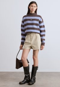 Καφέ και λιλά ριγέ πλεκτό πουλόβερ, μπεζ σορτς, μαύρες δερμάτινες μπότες μέχρι το γόνατο και μια μικρή καφέ τσάντα. Υφή και casual σχεδιασμός.