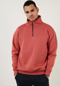 Helft-zip sweatshirt in koralen stof, met lange mouwen, ribgebreide manchetten en een licht gestructureerd oppervlak. Eenvoudig, schoon ontwerp zonder patronen.