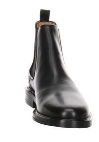 Botte Chelsea en cuir noir avec panneaux latéraux élastiques, un onglet de traction, une surface lisse et une semelle extérieure légèrement surélevée et texturée.