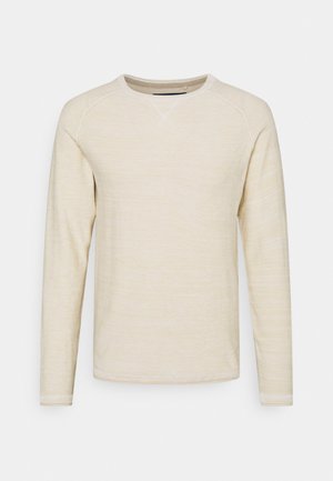 Lichtbeige lange mouw shirt van gestructureerde stof. Heeft een ronde hals en raglanmouwen met minimale stikdetails.