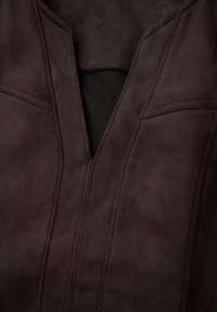 Bruine suède jacket met een V-hals ontwerp, subtiele stikdetails en een zwarte voering, met een gladde textuur.