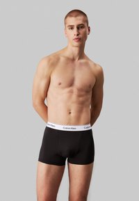 Sorte bomulls boxershorts med en hvit Calvin Klein logo midjebånd, med en tettsittende design og en glatt tekstur.