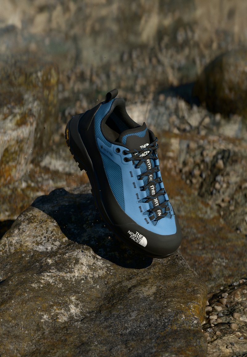 Blue and black hiking shoe with a sleek design, textured upper, laces, and a contrasting black sole. Features lacing system and logo accents.