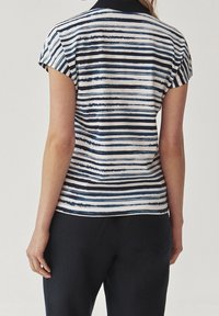 Haut à manches courtes rayé bleu marine et blanc avec col pointu et coupe décontractée. Tissu doux à la texture lisse.