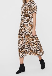 Maxi sukienka z lekkiego materiału, z pionowym wzorem w paski zebry w kolorze czarnym, pomarańczowym i białym. Krótkie rękawy i pasek w talii.
