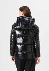 Chaqueta de plumas negra con un acabado brillante, que cuenta con capucha, paneles acanalados y un ajuste relajado. La vista trasera resalta la textura y el diseño.