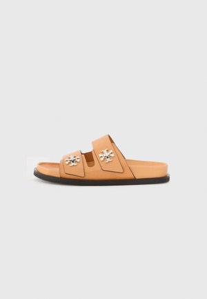 Sandalias deslizantes de cuero marrón con dos correas que presentan diseños de corte y herrajes plateados. Suela plana con un borde negro.