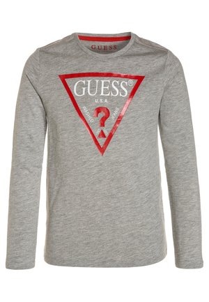 Chemise gris clair à manches longues avec un logo triangle rouge comportant le mot GUESS, un point d'interrogation et le texte « Washed Jeans » sur la poitrine.