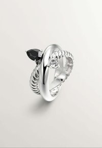 Anillo de plata con un diseño de banda retorcida, con una gema negra en forma de pera y una pequeña piedra clara redonda en extremos opuestos.