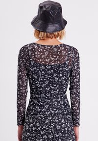 Haut à manches longues en maille noire à motifs floraux, au design ajusté et à fronces à la taille, présentant de délicats motifs de fleurs blanches.