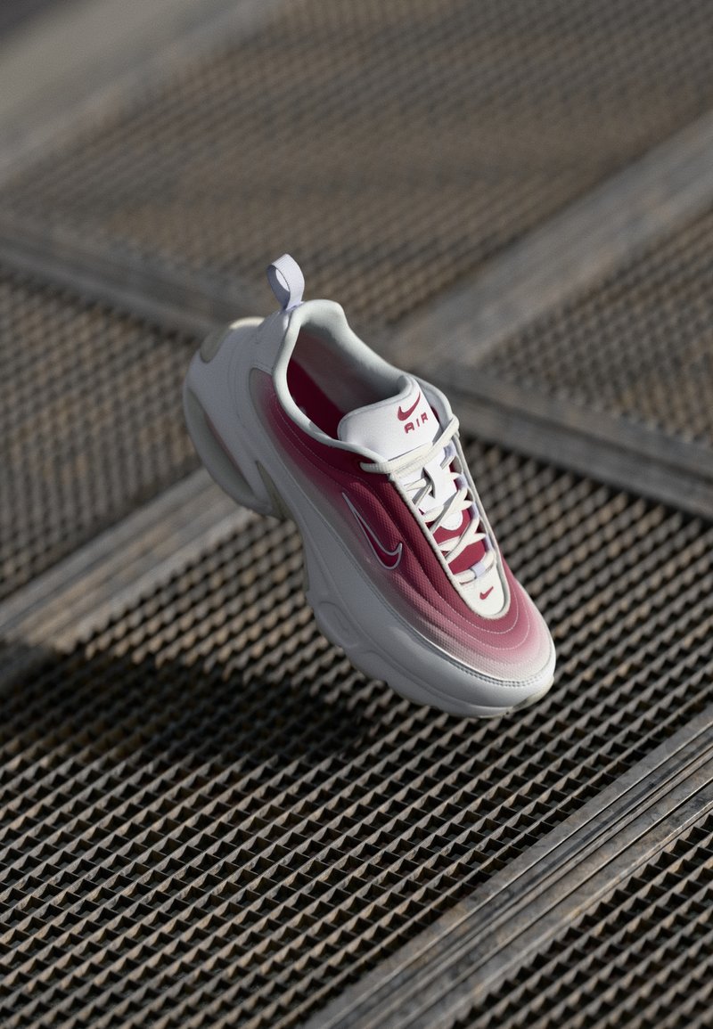 Nike Air tenisky v bielom s ružovými prechodmi, s textúrovanou podrážkou, šnurovacím dizajnom a pútkom na päte.