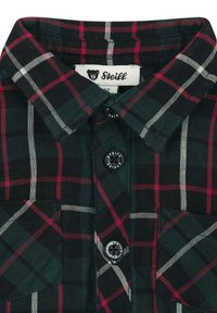 Camisa de cuadros verde con patrones de cuadros rojos y blancos, cuello de botón y dos bolsillos frontales. Botones negros con el logo de la marca.