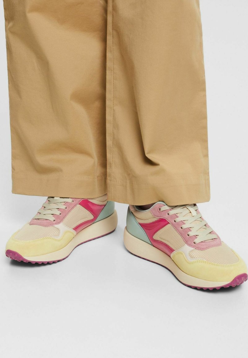 Baskets multicolores avec des panneaux en maille et lisses en rose, jaune et menthe. Semelles épaisses blanches avec des accents roses. Design léger.