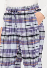 Pantalons de lounge à carreaux violets et bleus avec taille élastique et cordon de serrage. Comprend des poches latérales et un tissu doux et texturé.