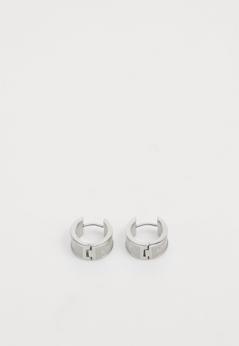 Orecchini a cerchio color argento con finitura texturizzata, caratterizzati da un design a chiusura. Bordo liscio e superficie interna lucida.