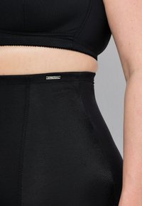 Top corto sportivo nero e leggings a vita alta realizzati in tessuto liscio ed elastico; presenta un'etichetta con logo e un design senza cuciture.