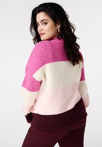 Colorblock gebreide trui met horizontale strepen in roze, lichtroze, crème en bordeaux. Zachte textuur met een losse pasvorm en geribbelde boorden.