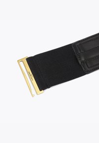 Czarny pleciony pasek z tkaniny z złotą prostokątną metalową klamrą i czarnymi skórzanymi detalami na jednym końcu.