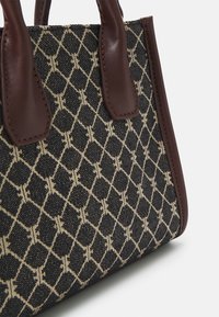 Brązowa torba typu tote z akcentami ze skóry, wykonana z fakturowanej, wzorzystej tkaniny w kolorach czarnym i beżowym z motywem diamentu oraz wyraźnym przeszyciem.