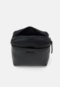Borsa cosmetica nera in ecopelle con chiusura a zip, texture liscia, forma rettangolare e nome del marchio impresso sul davanti.