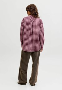 Lang�ærmet, ternet skjorte i nuancer af bordeaux og lyserød med afslappet pasform, rygskørt og rundet kant, kombineret med brune fløjlsbukser.