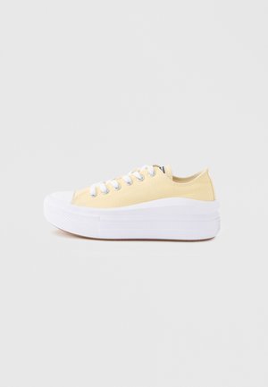 Plateau sneaker met een bovenwerk van lichtgeel canvas, witte rubberen neuskap, dikke witte zool en witte veters, zijaanzicht op witte achtergrond.