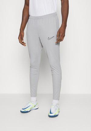 Grå træningsbukser med elastisk talje, med et sort Nike-logo på venstre side og tapered ben design.