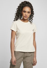 T-shirt corto color beige chiaro in morbido cotone, con collo rotondo e vestibilità comoda, abbinato a pantaloni cargo color khaki.