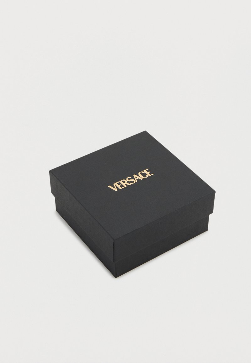 Black square Versace box with gold logo centered on lid, set against a plain light gray background.