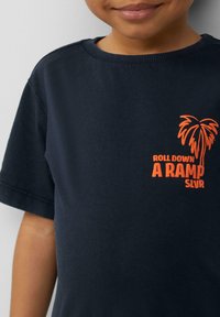 Donkerblauwe katoenen t-shirt met korte mouwen. Voorzien van een oranje palmboom graphic en de tekst "ROLL DOWN A RAMP SLVR" op de borst.