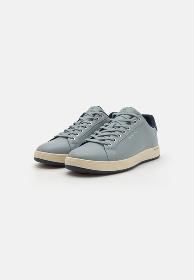 Helle blaue Sneaker mit einem glatten Synthetik-Obermaterial, cremefarbener Sohle und marineblauen Akzenten. Mit flachen Schnürsenkeln und einem runden Zehenbereich.