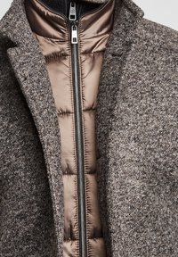 Cappotto in misto lana con motivo a spina di pesce grigio, dotato di uno strato imbottito con zip di un lucido taupe, con texture e colori a contrasto.