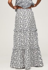Floraler, mehrlagiger Maxirock in Weiß mit marineblauem Blättermuster, mit Rüschenlagen und einem elastischen Bund für Komfort und Passform.