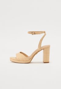 Sandales à talons hauts beiges avec un dessus en tissu texturé, une large sangle au niveau des orteils, une sangle à la cheville avec boucle ajustable, et un talon moyen.