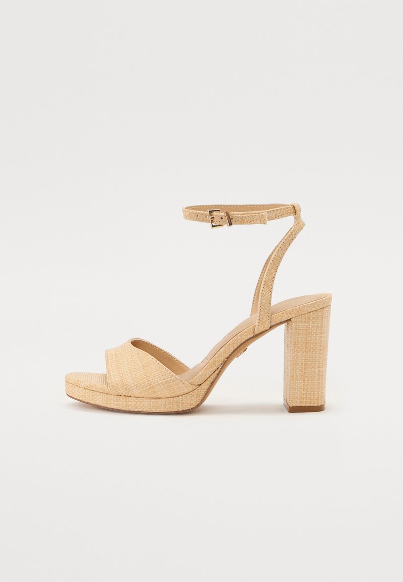 Sandales à talons hauts beiges avec un dessus en tissu texturé, une large sangle au niveau des orteils, une sangle à la cheville avec boucle ajustable, et un talon moyen.