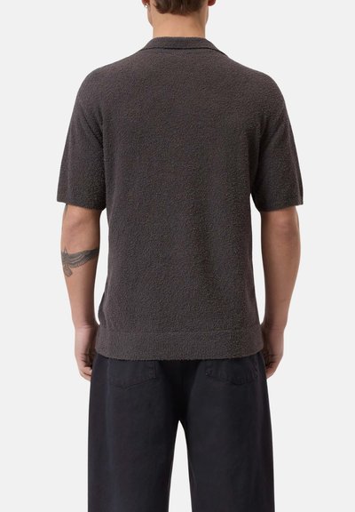 Polo shirt a maniche corte, grigio scuro, con tessuto texturizzato, colletto ribattuto e orlo. Presenta una vestibilità comoda e dettagli minimi.