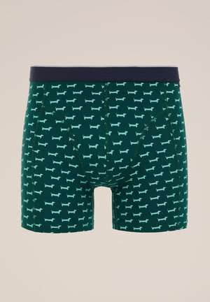 Groene boxershorts met blauwe teckelpatroon, een marineblauwe elastieken tailleband en een zachte katoenmix stof. Heeft een traditionele snit.