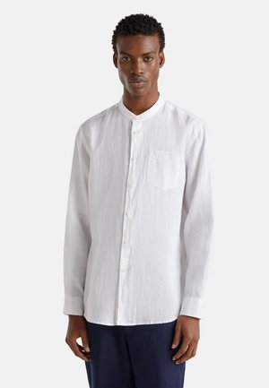 Biała lniana koszula z długimi rękawami, kołnierzykiem typu band, z przodu na guziki oraz jedną naszywaną kieszonką po lewej stronie. Gładki, teksturowany materiał.