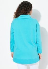Pullover turchese con colletto alto, maniche lunghe e spacchi laterali. Realizzato in un materiale morbido, presenta una vestibilità comoda e una texture liscia.