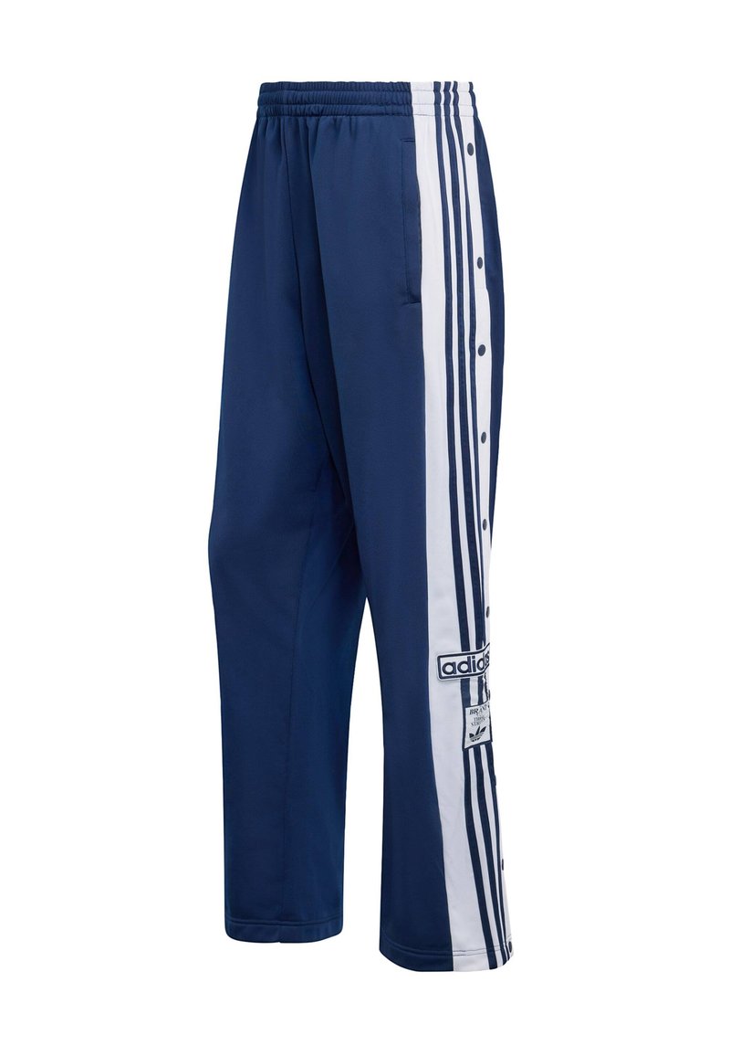 Marineblaue Trainingshose mit weißen Seitenstreifen, Druckknöpfen und einem Adidas-Logo-Patch. Hergestellt aus leichtem Stoff mit glatter Textur.