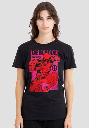 Young woman wearing black T-shirt with red graphic of Deadpool crouching and text "Deadpool The Merc With The Mouth" on front.