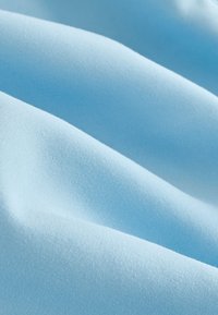 Tissu bleu clair à la texture lisse, présentant des drapés doux et fluides ainsi qu'une légère brillance, mettant en valeur son tissage régulier et sa douceur.