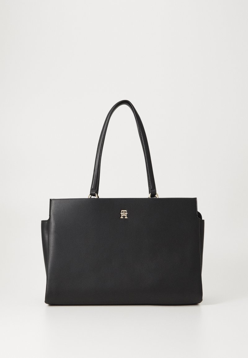 Black leather tote bag with two top handles, featuring a gold logo on the front, smooth texture, and structured rectangular shape.