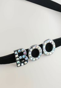 Schwarzer elastischer Haargummi mit den Buchstaben "B", "O" und "O", die mit mehrfarbigen Strasssteinen in einer kreisförmigen Anordnung verziert sind.