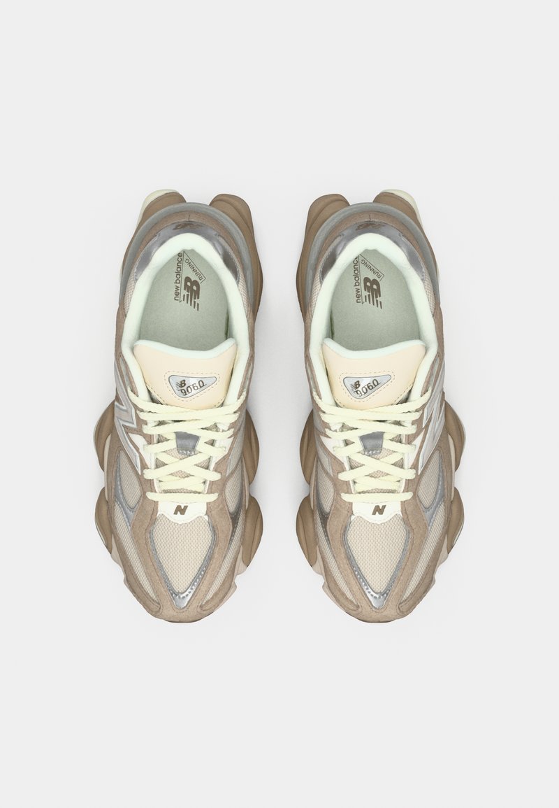 Beige en grijze sneakers zijn gemaakt van mesh en suède materialen, met een stevige zool, ronde neus en crème veters. Opvallende branding op de tong.