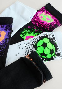 Négy pár sport zokni fekete, fehér és lila színben, színes fröccsentett mintákkal, focilabda motívumokkal neon rózsaszín, zöld és narancssárga színekben.