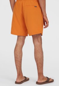 Bañador naranja con cintura elástica, un bolsillo trasero y una tela suave y ligera. El diseño es sencillo con líneas limpias.